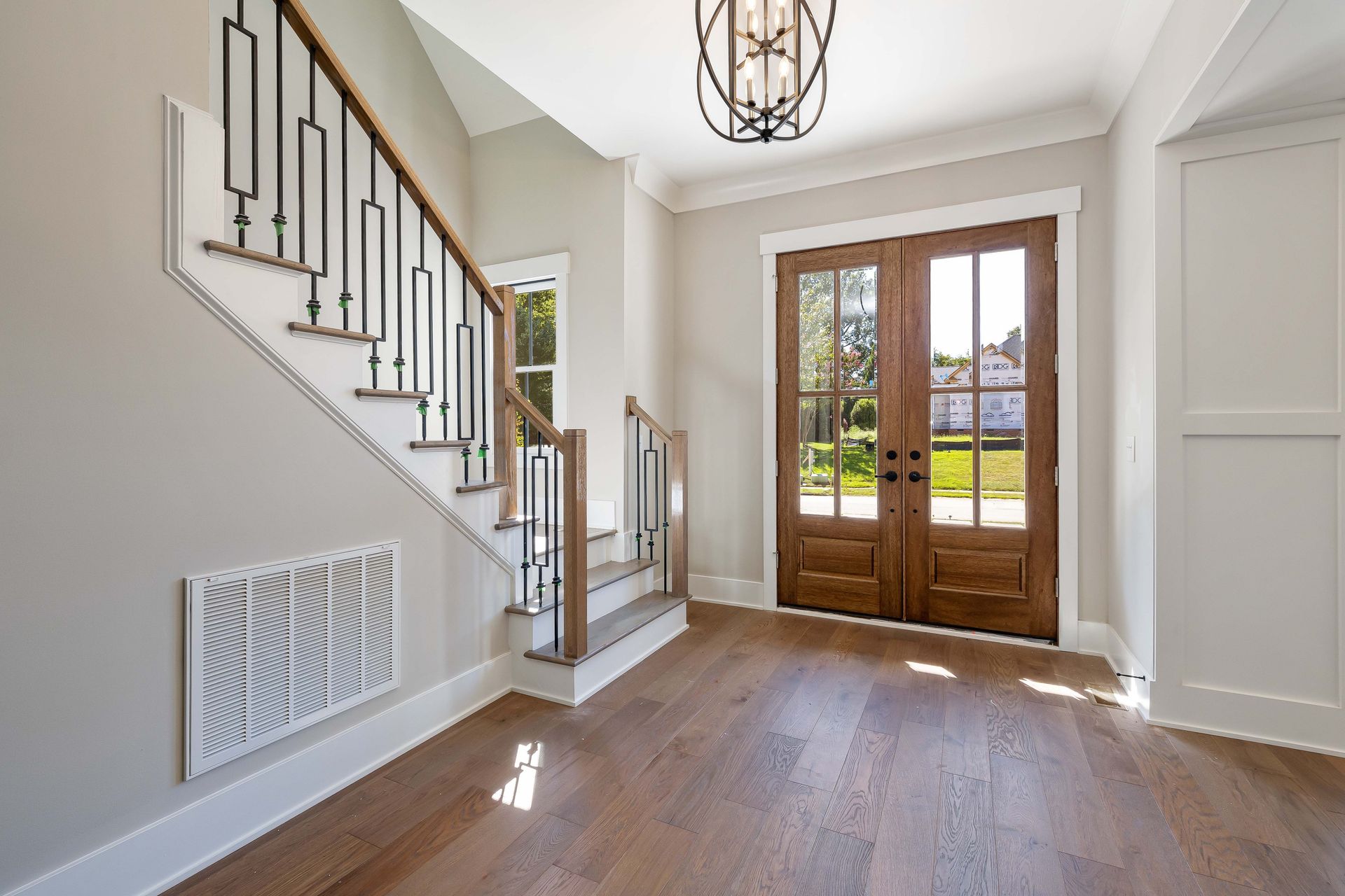 Elegant and spacious house entrance featuring wooden doors and staircase.